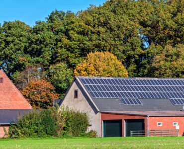 Barns with solar panels in a grassy field.