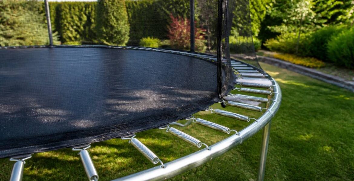 Trampoline met veiligheidsnet in een tuin, klaar voor gebruik