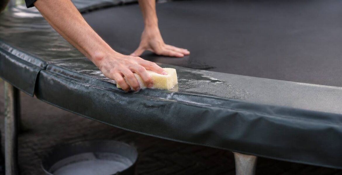 Schoonmaken van trampoline springmat en randkussen met spons en lauwwarm water