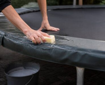 Schoonmaken van trampoline springmat en randkussen met spons en lauwwarm water
