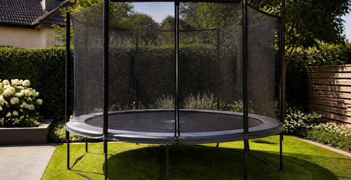 Trampoline met veiligheidsnet en randkussen in een tuin, klaar voor gebruik