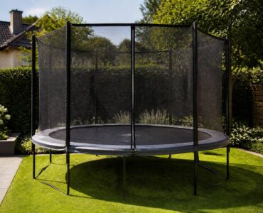 Trampoline met veiligheidsnet en randkussen in een tuin, klaar voor gebruik