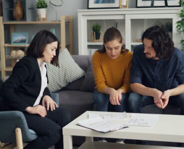 three people sitting on a couch in a living room