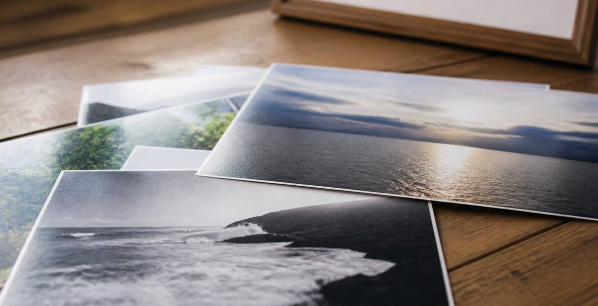 Close-up van fotoprints met verschillende afwerkingen op een houten tafel, onder natuurlijk licht