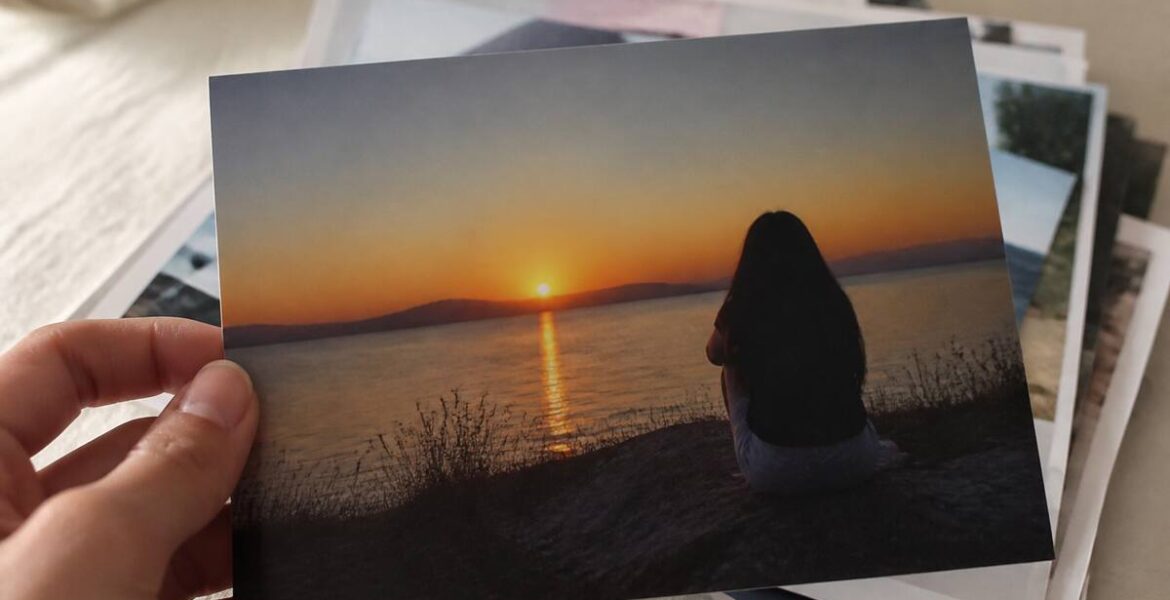 Hand die een afgedrukte foto vasthoudt op mat papier bij daglicht