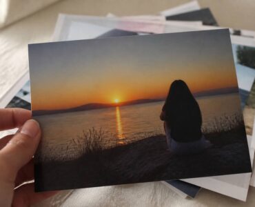 Hand die een afgedrukte foto vasthoudt op mat papier bij daglicht